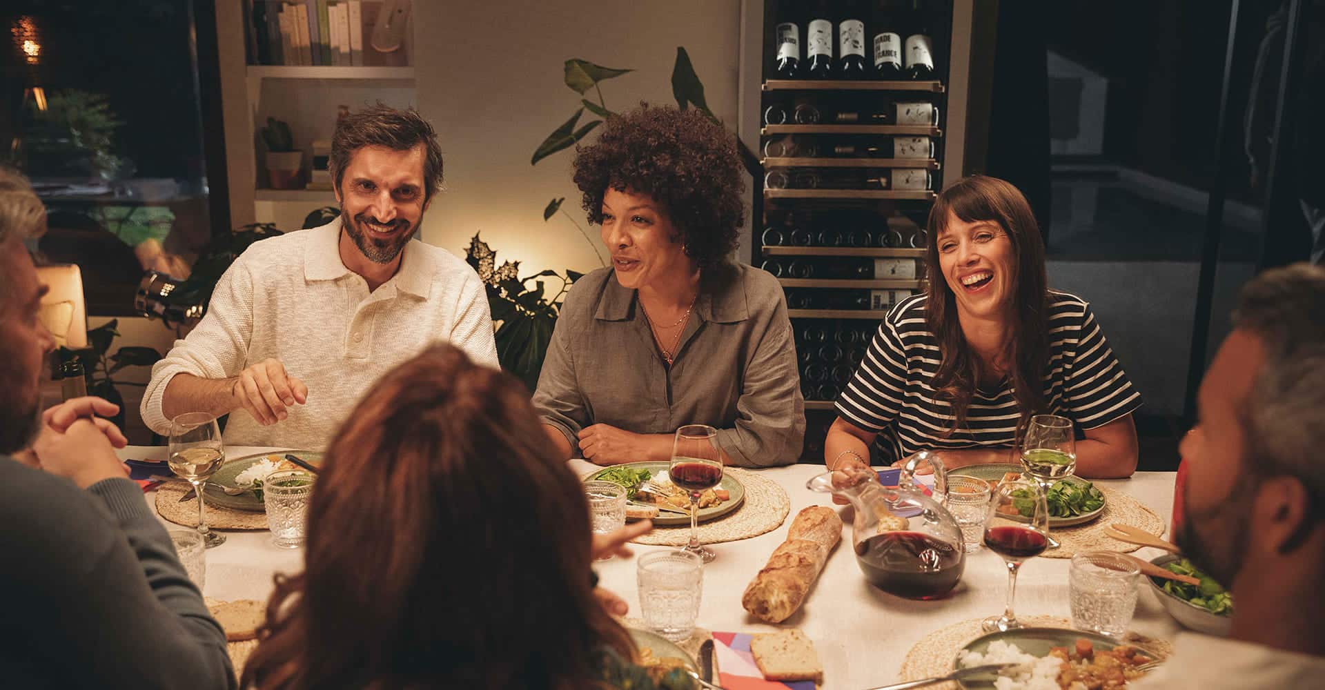 6 personnes autour d'une table partagent un repas en intérieur