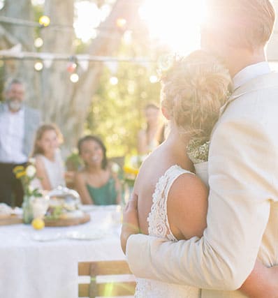 Un couple de mariés de dos et quatre invités près d'une table.