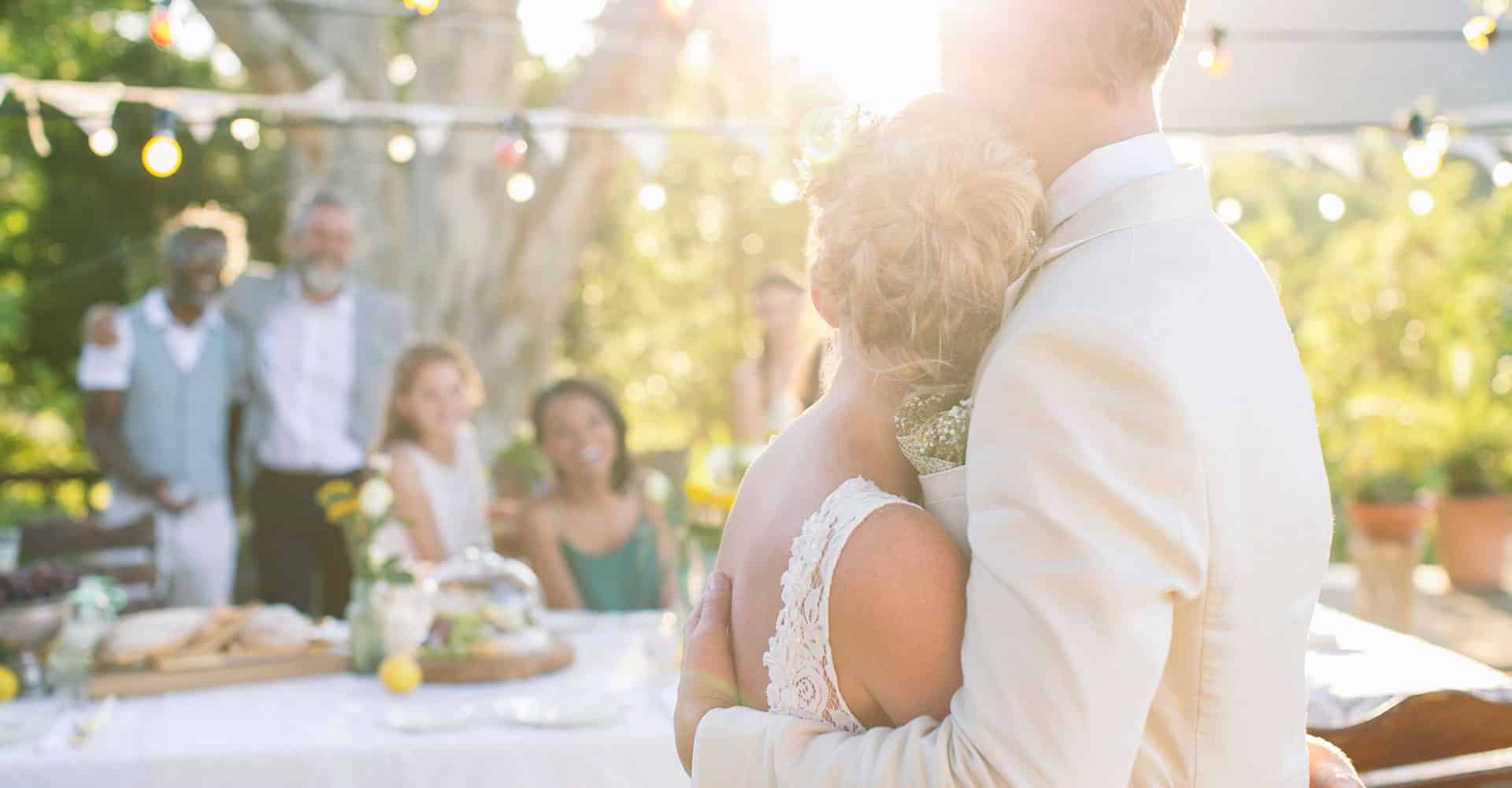 Un couple de mariés de dos et quatre invités près d'une table.