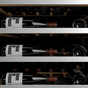 Des bouteilles de vin sont posées sur trois étagères grises à l'intérieur d'une cave à vin
