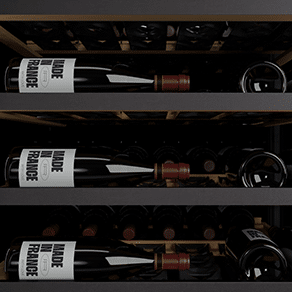 Des bouteilles de vin sont posées sur trois étagères noires à l'intérieur d'une cave à vin