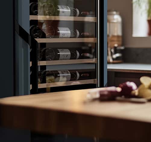 Une table en bois et une cave à vin noire vitrée avec 4 étagères.