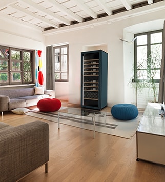 Un grand salon gris et deux poufs rouge et bleu avec une cave à vin au milieu.