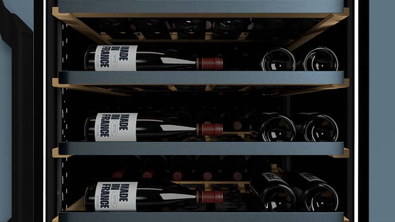 Plusieurs bouteilles de vin couchées sur trois clayettes noires dans une cave à vin.
