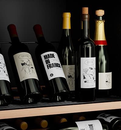 Un gros plan sur une étagère de cave à vin avec six bouteilles en position verticale.